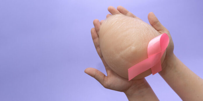 Silicone breast prosthesis on woman hands and Pink Ribbon. Breas Pretty-in-Pink