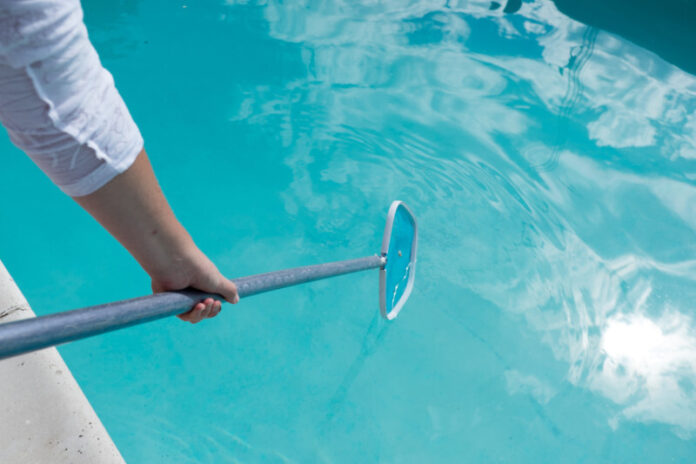 Woman skimming leaves and debris out of a private home swimming