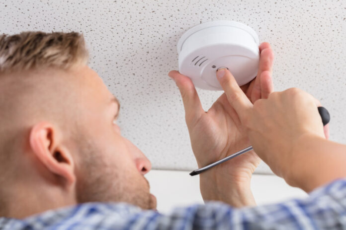 Low,Angle,View,Of,A,Person's,Hand,Installing,Smoke,Detector