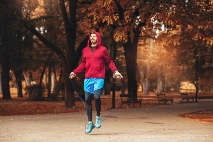 Man jumping rope outdoors on sunny autumn morning.