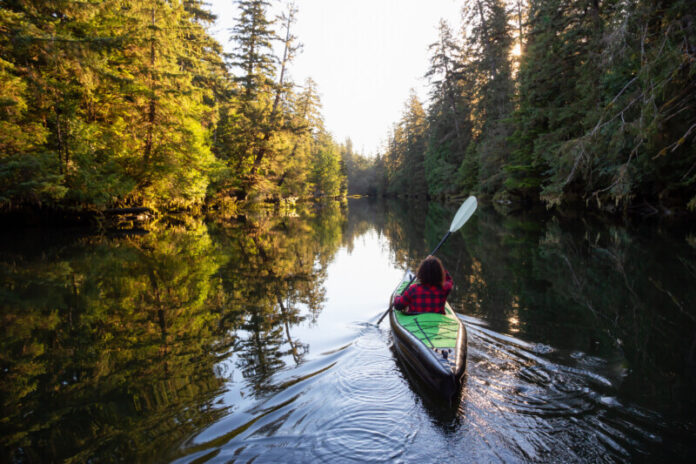 Girl kayaking in the river during a sunny summer morning.