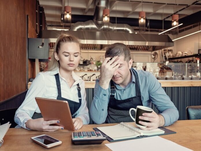 Depressed male and female entrepreneurs overwhelmed by finance problems - Nervous manager checking restaurant finance - Failure in small-business concept