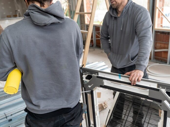 Hvac technicians installing air conditioning unit at construction site Should I retrofit or replace my HVAC system?